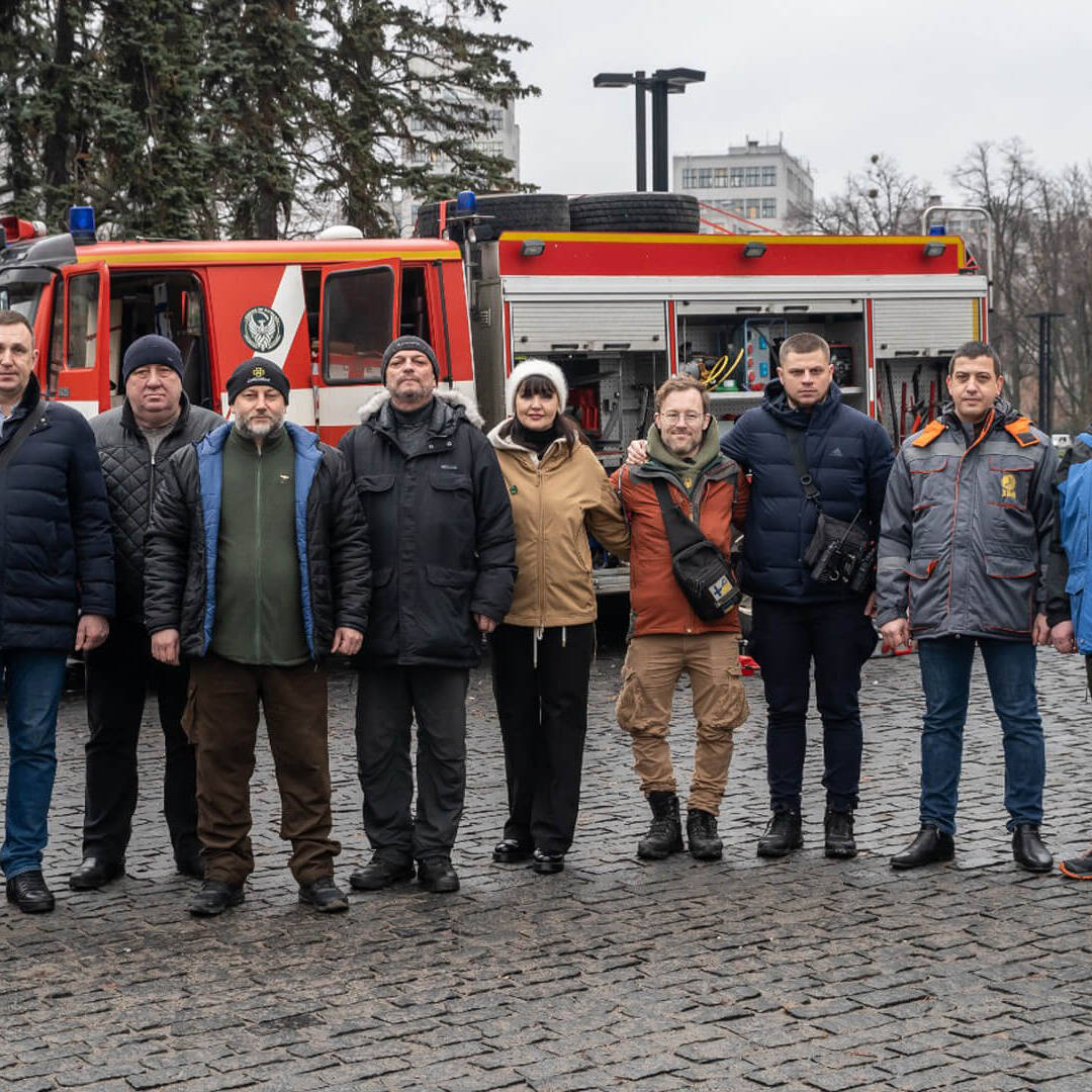 Feeniksin Kilta ry:n ensimmäinen tehtävä yhdistyksenä oli paloauton toimittaminen Harkovan kaupungin pelastuspalveluille. Tässä ryhmäkuva ikonisen Derzhpromin edustalla.